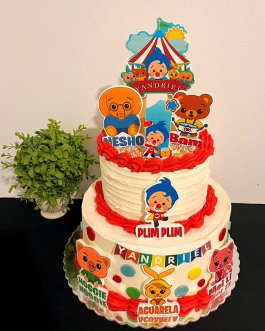 Pastel de cumpleaños de dos niveles decorado con personajes infantiles y colores vibrantes.