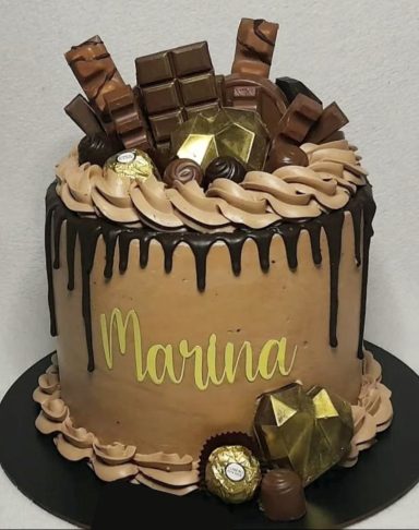 Tarta decorada con chocolate, bombones y el nombre "Martina" en la parte frontal.