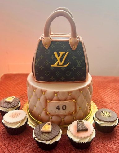 Tarta grande en forma de bolso de diseñador con cupcakes decorados a su alrededor.