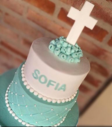 Tarta decorada en tonos aqua con una cruz blanca y el nombre "SOFIA".