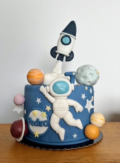 Tarta temática espacial con un astronauta, cohete y planetas coloridos.