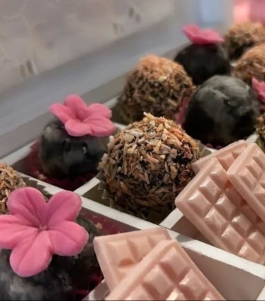 Bombones decorados con flores y tabletas de chocolate en una caja.