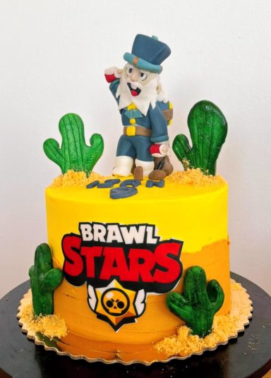 Tarta decorada con un personaje de "Brawl Stars" y cactus, fondo amarillo.