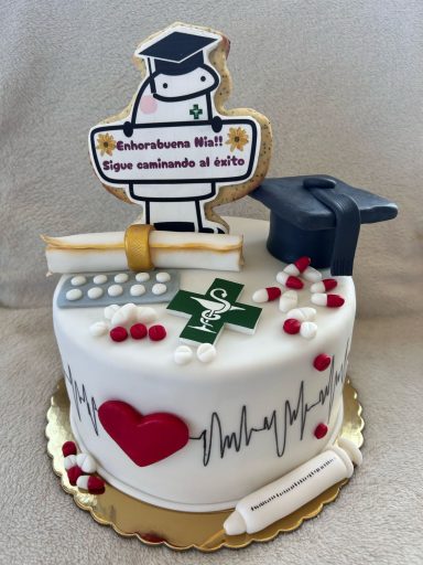 Tarta decorada con un graduado, un gorro, un diploma y elementos médicos.