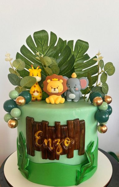 Tarta decorada con animales de safari y el nombre "Enzo" en un fondo verde.