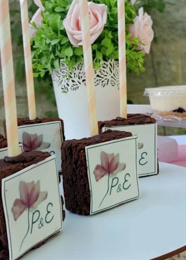 Dulces de chocolate decorados con flores y palitos de papel en una mesa festiva.